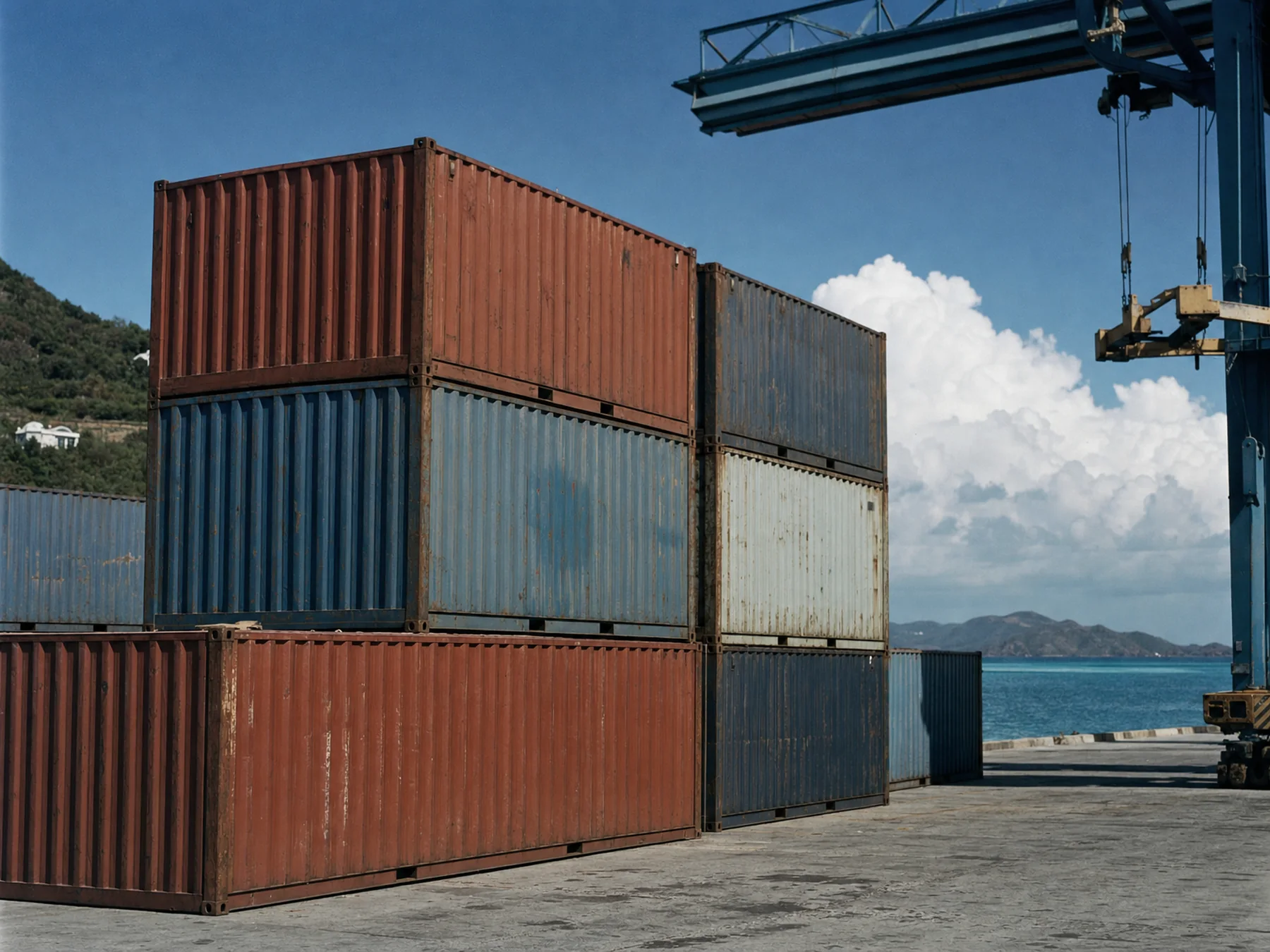 Containers stacked on a Caribbean quayside beneath a gantry crane